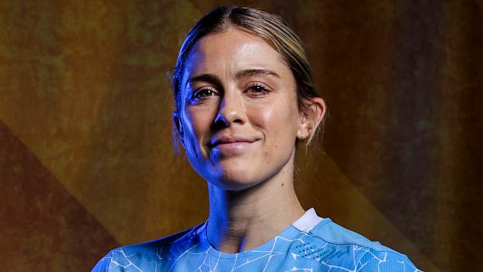 Abby Dahlkemper poses in a light blue soccer jersey and wears her dirty blonde hair in an up-do.
